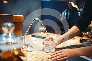 Male barista pours filtered water into the glass