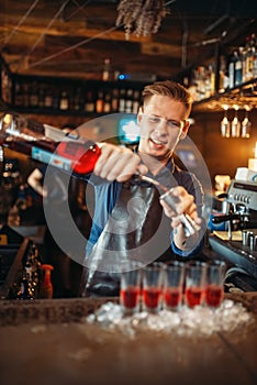 Male barman in apron prepares alcoholic coctail