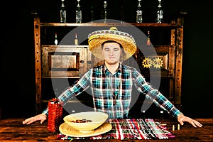 Male bartender in a sombrero standing at the counter, bottle of