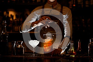 Male bartender stirring a cocktail in the measuring glass cup