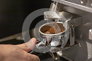 Male bartender on the workplace. Closeup image of male hands while making coffee using coffeegrinder and coffeemachine