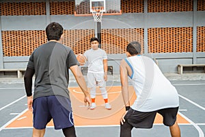 a male basketball player carrying the ball is blocked by two opposing players in a ready position