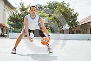 a male basketball player performs a low dribble with the ball while practicing basketball