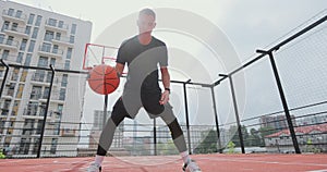 Male basketball player practicing ball handling skill on basketball court. Man basketball player training alone. Workout