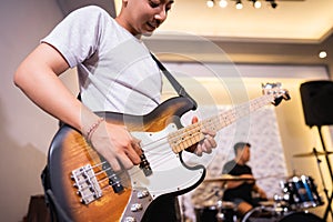 a male bassist plays an electric bass guitar during rehearsal with his band