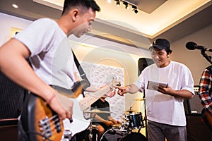 a male bassist plays an electric bass guitar with a vocalist during tuning