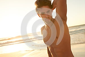 Male beauty at the beach. a handsome shirtless young man standing on the beach at sunset.