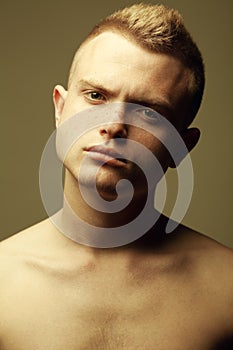 Male beauty concept. Portrait of fashionable and undressed young man with stylish haircut posing over mustard background. Perfect