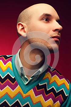 Male beauty concept. Profile portrait of a smiling elegant young & handsome bald man in stylish sweater posing over purple