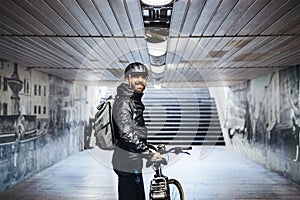 Male bicycle courier standing in subway when delivering packages in city.