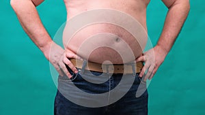 Male with a big belly shows his fat on a green screen. The concept of healthy eating and losing weight, diet
