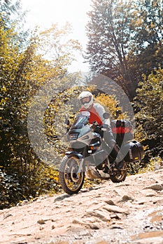 Male biker, motorcyclist in a white helmet rides a motorcycle. Long-distance touring motorbike. Side bags and luggage. mountain