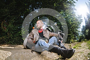 Male biker sitting on dirt road near motorcycle