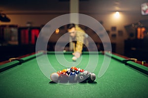 Male billiard player with cue aiming at the table