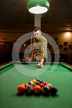 Male billiard player with cue aiming at the table