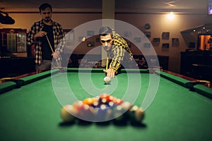 Male billiard player with cue aiming at the table