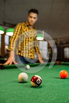 Male billiard player with cue, view from the table