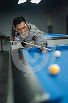 male billiard player poking the ball seriously using the cue stick