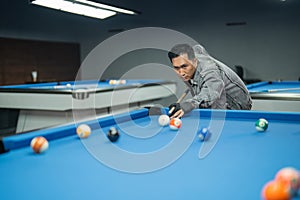 male billiard player poking the ball seriously using the cue stick
