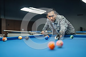 male billiard player poking the ball seriously using the cue stick