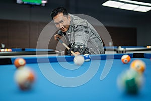 male billiard player poking the ball seriously using the cue stick