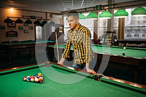 Male billiard player, poolroom on background