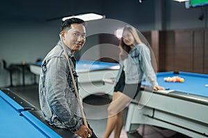 male billiard player standing leaning on the billiard table holding the stick