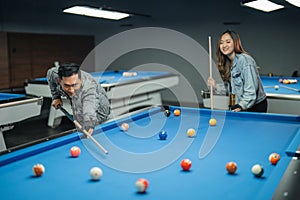 male billiard player targeting the object balll while the cue stick