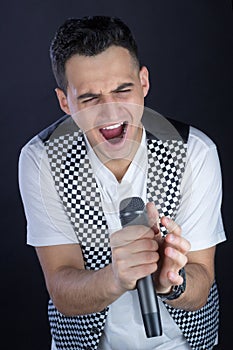 Male black-haired rock singer performs singing to microphone