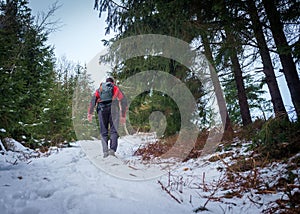 Muž s modrou a červenou bundou na turistike po snehu v lese v Telgárte, Slovensko