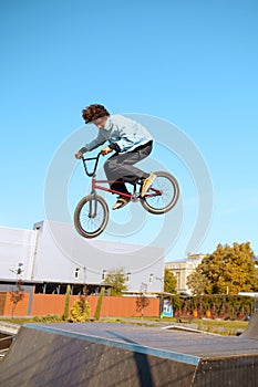 Male bmx biker doing trick on ramp in skatepark