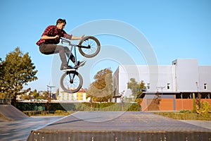 Male bmx biker jumps on ramp in skatepark