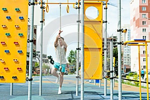 male bodybuilder athlete, trains on a street sports field. pull-up on a rope