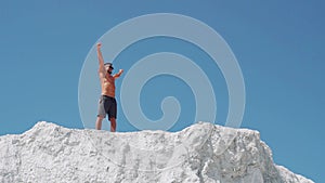 Male bodybuilder celebrates victory raising his arms high.