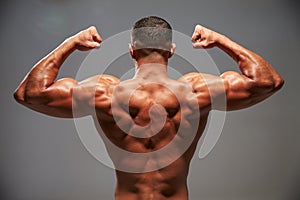 Male bodybuilder flexing his biceps, back view