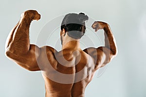 Male bodybuilder posing in studio, showing biceps