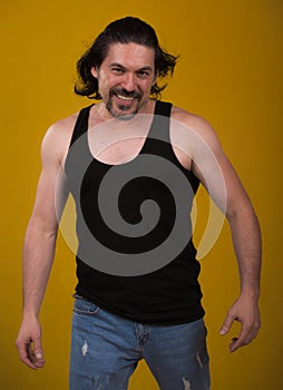 Male bodybuilder wearing dark tanktop on ripped muscular torso in studio shot