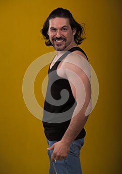 Male bodybuilder wearing dark tanktop on ripped muscular torso in studio shot