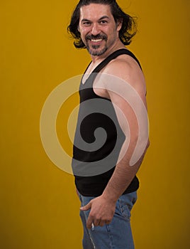 Male bodybuilder wearing dark tanktop on ripped muscular torso in studio shot