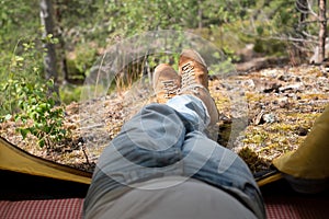 Male boots looking out of the tent during rest after hiking.