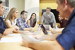 Male Boss Addressing Meeting Around Boardroom Tabl