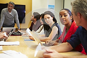 Male Boss Addressing Meeting Around Boardroom Table