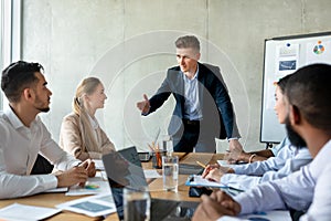 Male boss discussing company strategy with colleagues during corporate meeting in office