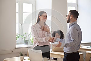 Male boss handshaking employee congratulating with promotion