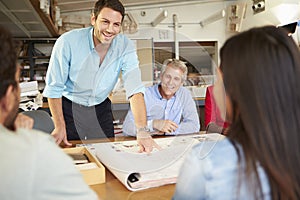 Male Boss Leading Meeting Of Architects Sitting At Table