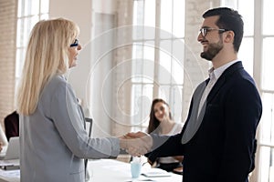 Male boss shake hand of female employee congratulate with promotion