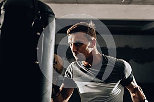 Male boxer in boxing gloves training with punching bag
