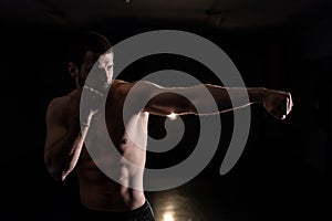 Male boxer doing shadow boxing inside a boxing ring. Boxer practicing her punches at a boxing studio. Black background
