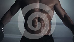 A male boxer shows a press and muscles. Close up. Boxing ring background. Naked athlete posing on camera.