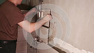 male builder applies mortar to the wall and glues light tiles to the wall in the bathroom